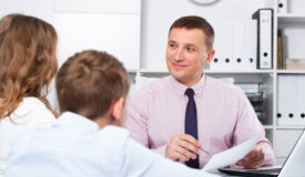 Middle-aged mother and son visiting consultation with school headmaster
